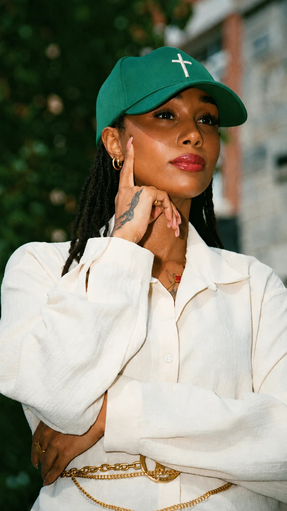 Her Mindset Essentials founder — confident and poised in cream outfit with green cap and gold accessories